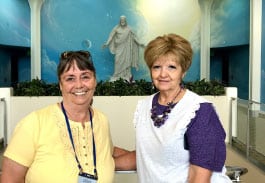 Two Female Visitors Posing In front Of The Christus Statue At The Independence Visitor's Center