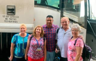 Group Of Visitors Posing In front Of Tour Bus
